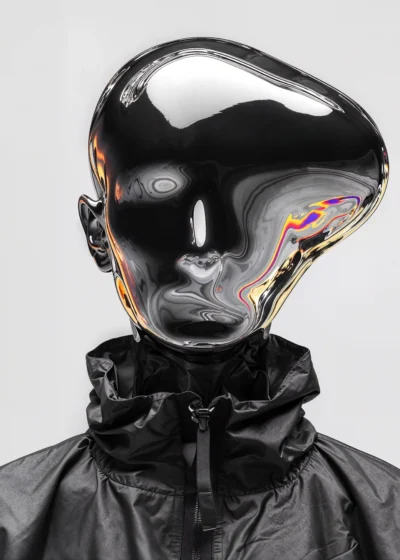 A silver chrome mirror figure with an abstractly shaped head reflecting distorted surroundings